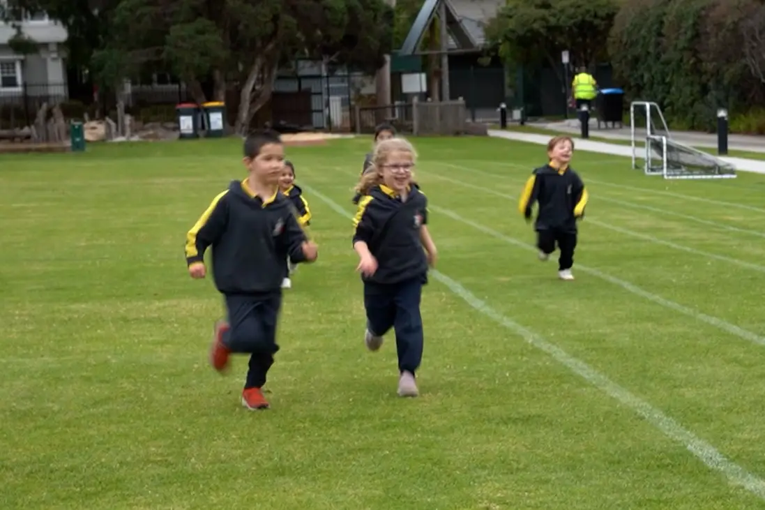 Five school kids running on a track field