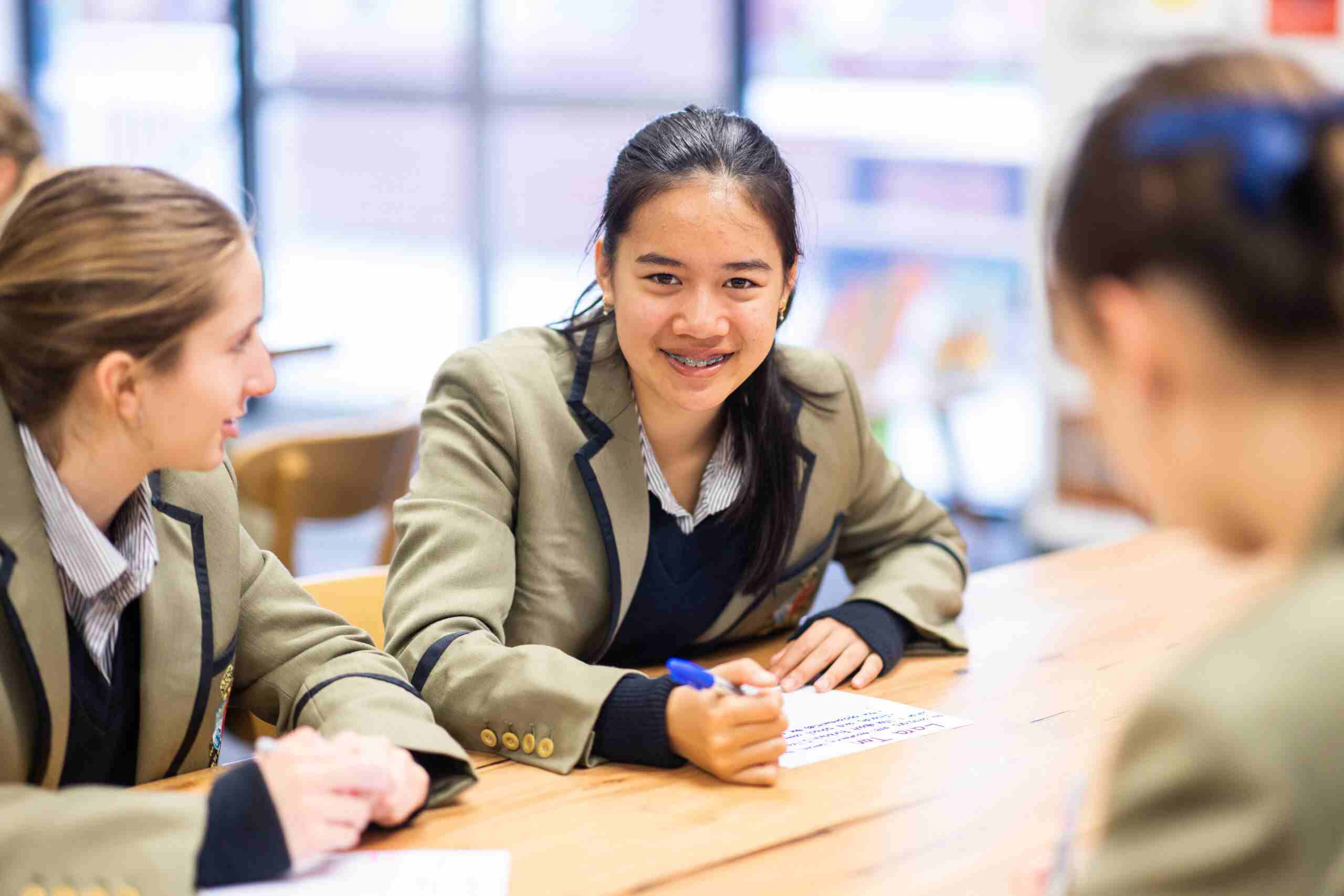 Three female students writing on paper