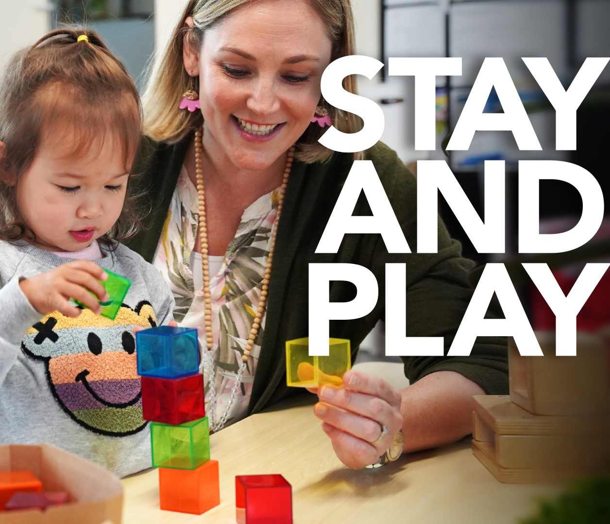 A female teacher assisting a girl in playing with blocks