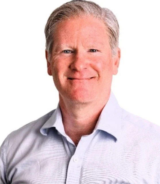 Smiling man with short, light hair wearing a light blue collared shirt