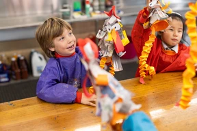 Children in art class happily showing their handmade crafts with colorful paper decorations